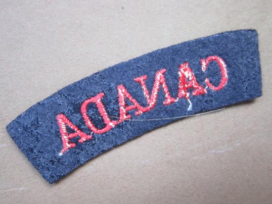A good British made embroided glue i.e paste backing red on black Canada shoulder title ... Combined Operation/Navy ??