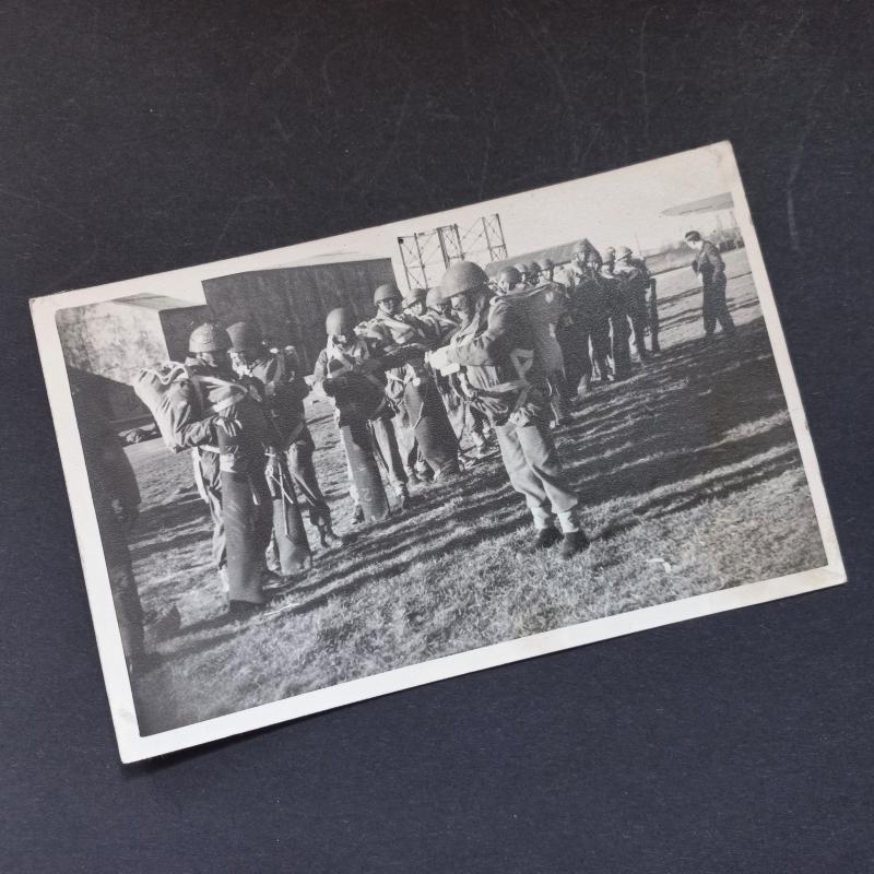 A great and original black and white postcard size (measuring 13.8cm by 8.8cm) photograph dispicting men of a Parachute unit getting ready for a most likely practice jump in full kit including Enfield or Bren valise's