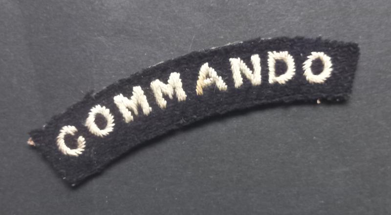 A superb - albeit regrettably single - early white on black embroided commando shoulder title